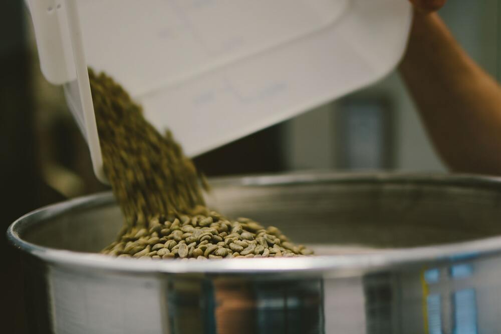 Grains de café verts mis dans un torréfacteur